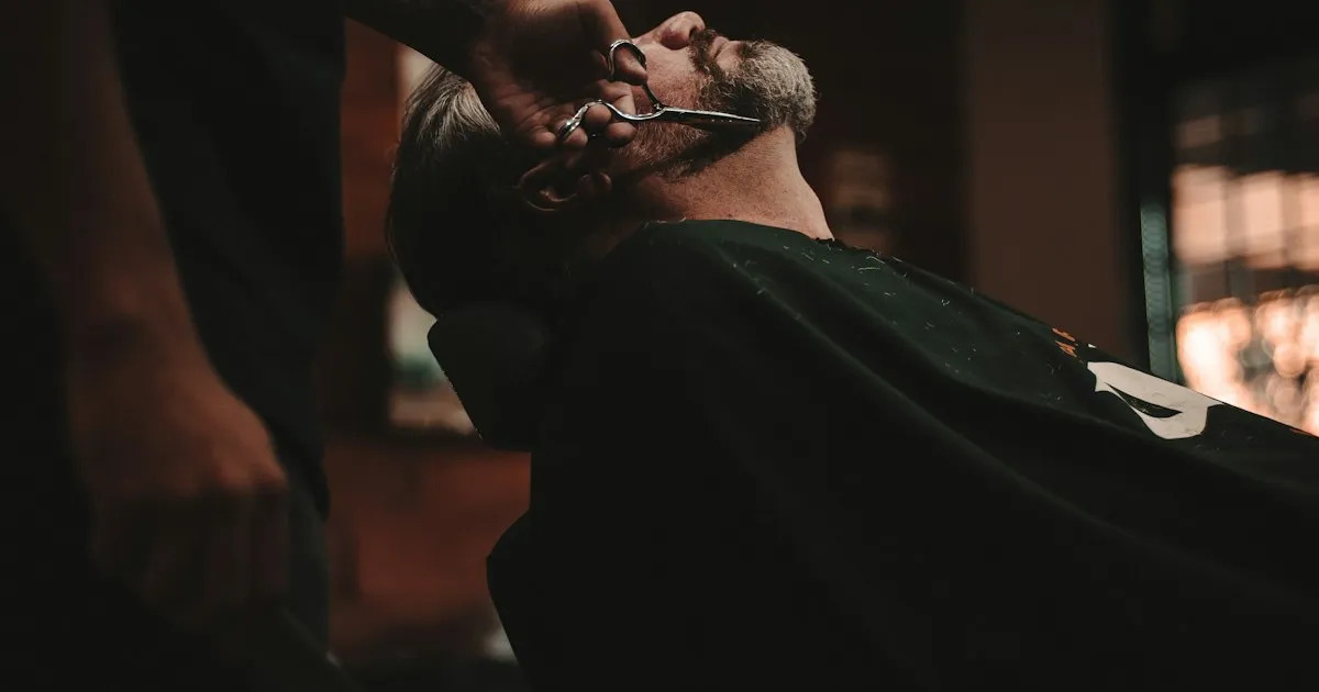 Barbier taillant la barbe d'un client aux ciseaux dans un salon
