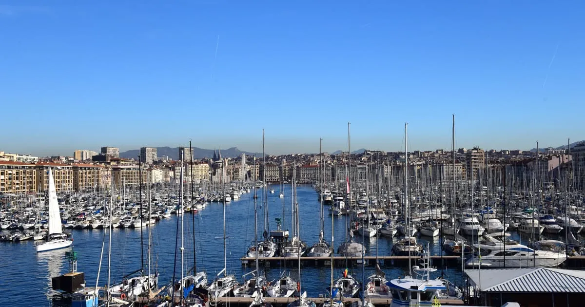 Le Vieux-Port de Marseille sous un ciel bleu, avec ses voiliers amarrés et la ville en arrière-plan