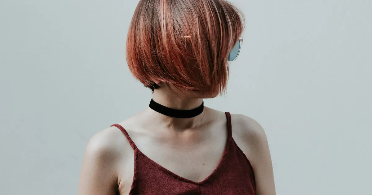 Femme de profil portant un carré plongeant cuivré, les pointes effleurant la mâchoire