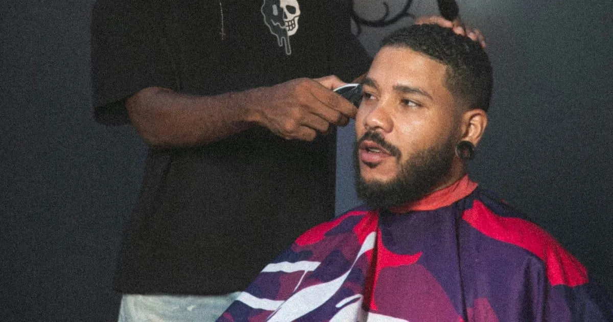 Barbier réalisant un dégradé à la tondeuse sur les tempes d'un client